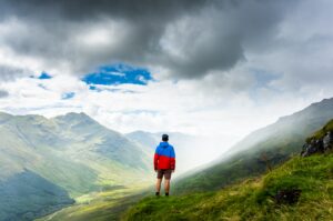 A man nearly touching the clouds as he looks down across the mountainside to the valley. Its about the AND between the extremes.