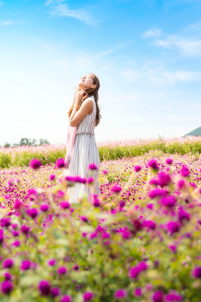 A woman in a field of purple flowers looking up to the blue skies in gratitude for the beautiful results of her changes that were both deeply personal and a community affair.