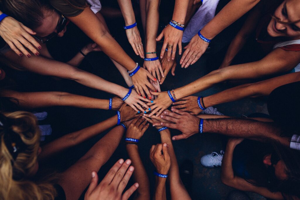 Tens of hands joining at the center of a circle showing belonging that we are afraid of losing when we feel like a fraud.