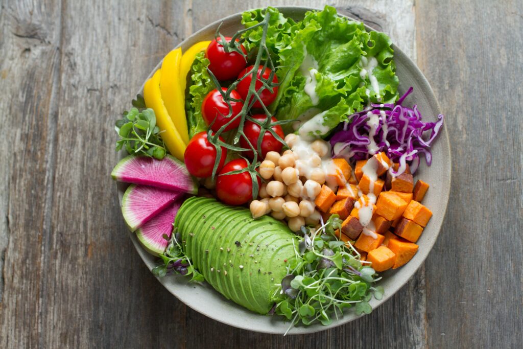 A brightly colorful, healthy vegetarian platter of avocado, sweet potato, chickpea, lettuce and tomato.