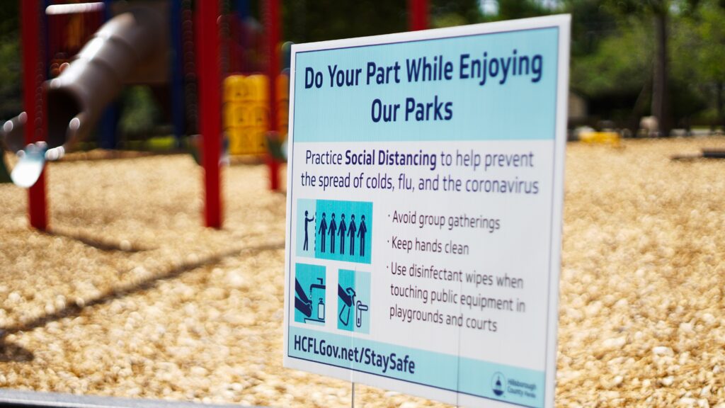 A sign posted at a playground about doing our part to social distancing ourselves from others.