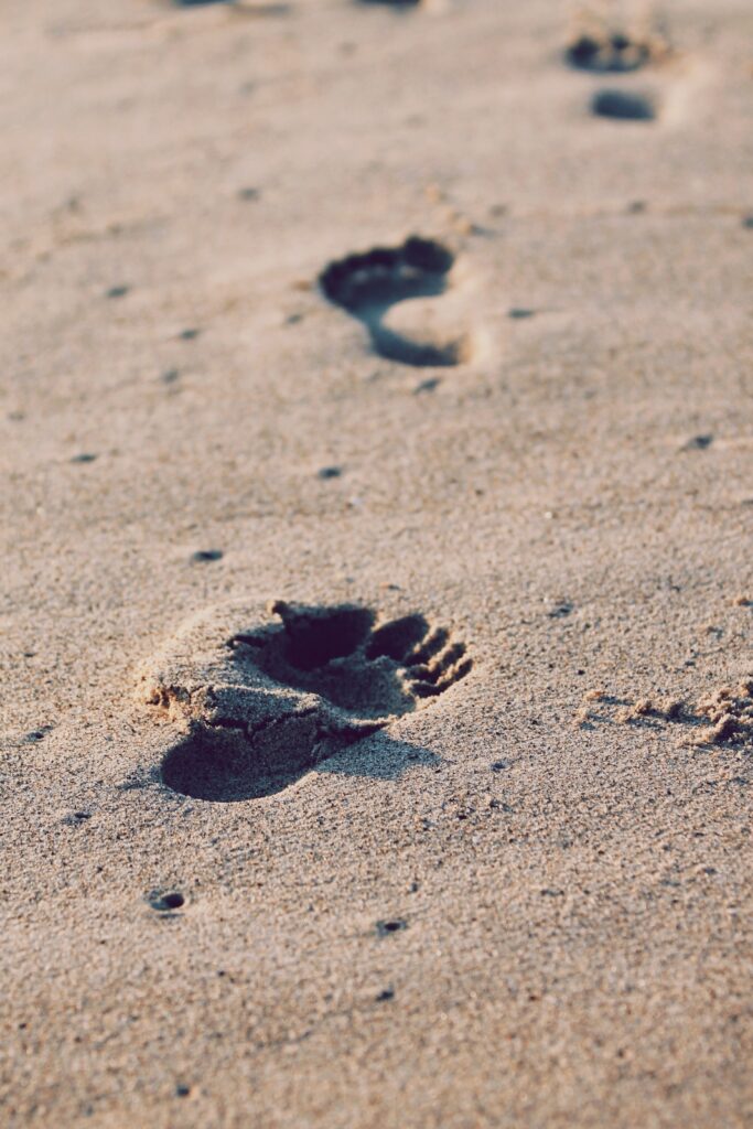 Footsteps in sand demonstrating faith in power of one next best move after another