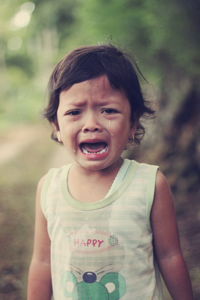 Sad young girl crying. Her shirt says happy, but is wet with tears. Noone is helping her cope.