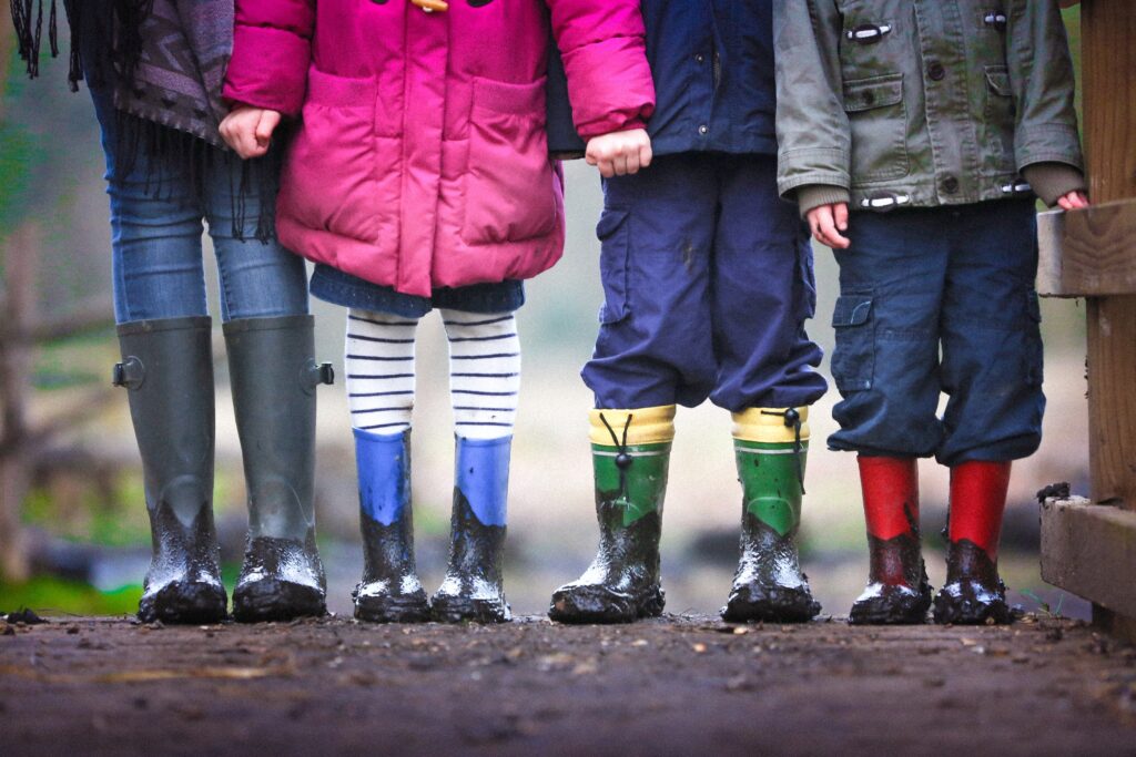 4 sets of boot clad kids legs on a muddy path