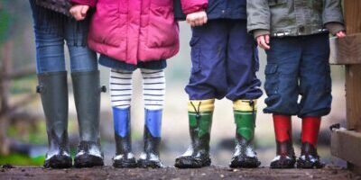 4 sets of boot clad kids legs on a muddy path