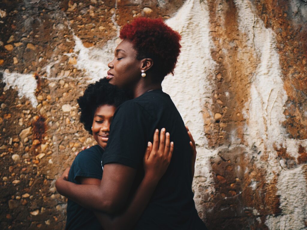 An African American Mother is helping her child cope by giving her a big hug.