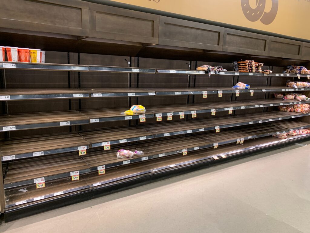The vacant shelves of the grocery store with scattered loaves of bread. Are the feelings behind the mask distress?