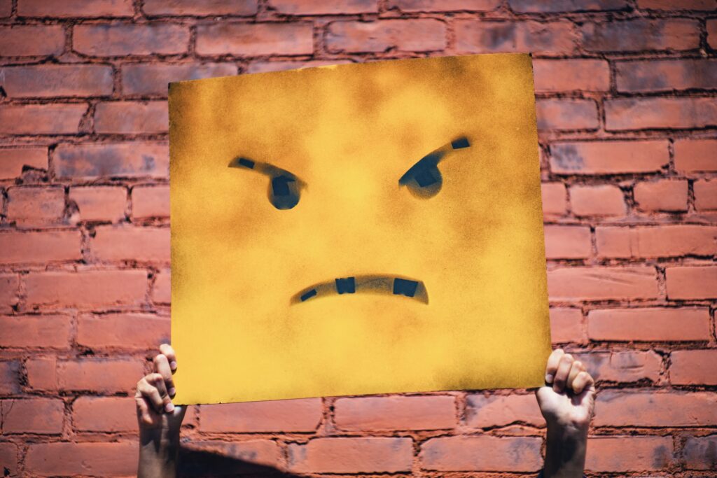 A piece of yellow sheet metal with an angry, hateful face representing vitriol of snap judgment s being made right now.