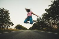 A woman jumping in the streets after following 6 steps to bouncing back from hard times.
