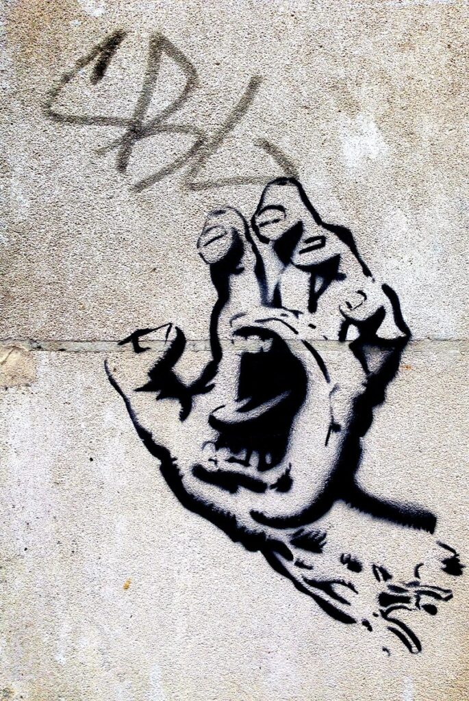 Graffiti artwork of a outstretched half clenched palm with open angry mouth In the center.