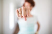 Blurred image of a woman with outstretched fist in focus with ring that says I am a bad ass showing you how to take back your power