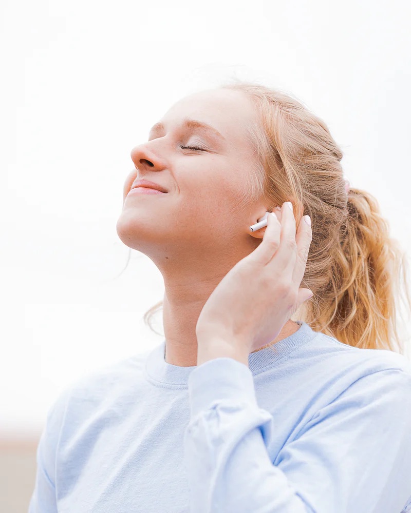 A woman with earbuds face to the sky with a smile as she learns how to toad better care of her brain
