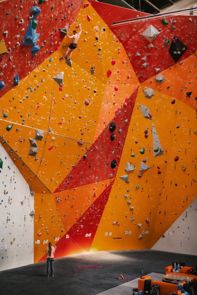 A man at the top of a massive climbing wall having overcome immense obstacles