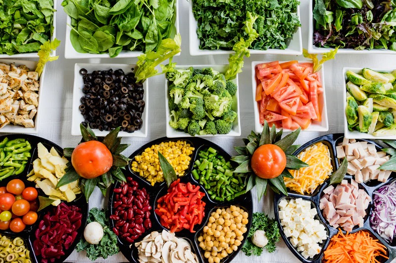 Numerous trays of vibrantly colored fruits and vegetables representing clean, Whole Foods that support healthy metabolism