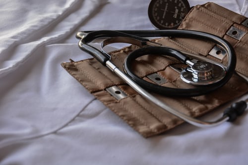 A doctor's stethoscope and surgical tool kit laid across a white sheet