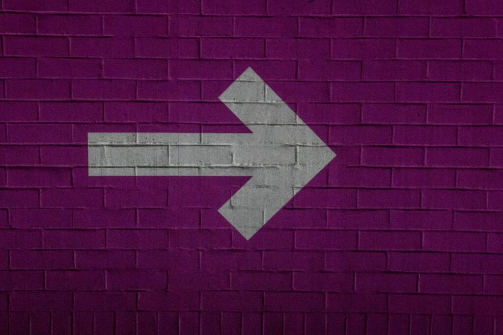 White arrow on purple brick pointing forward