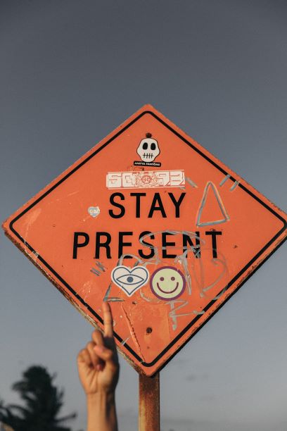 Orange Road Sign that says Stay Present