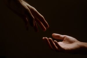 A hand in the darkness reaching out to another
